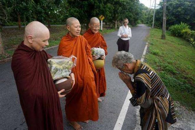 Three bhikkhunis receive alms and offer blessings in the northern village of Talad Mai. Photo by Denis Gray. From asia.nikkei.com