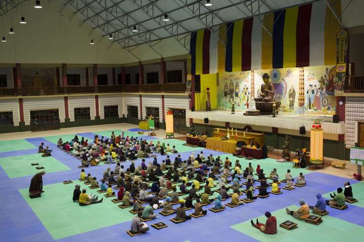 A Buddhist service in Swaziland, with a monk overseeing the proceedings. Sitting next to the children, the care mothers. From aljazeera.com