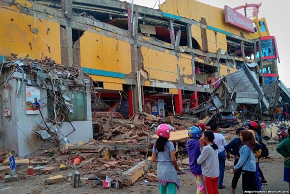 Residents stand in front of a damaged shopping mall after an earthquake hit Palu, Sulawesi Island, Indonesia, Sept. 29, 2018.