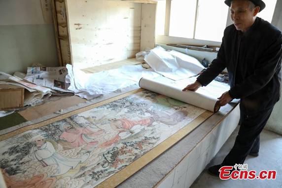 Zhang Zhanping shows his scrolls featuring a Buddhist scripture about 1,250 Arhats, a perfected person who has achieved spiritual enlightenment, in Daixian County, Xinzhou City, North China\'s Shanxi Province, March 18, 2019. The 66-year-old farmer, also a local folk artist specializing in the making and painting of Buddhist sculptures, said he spent eight years creating nine scrolls, each weighing five kilograms and measuring 69 centimetres in width. The total length of the scrolls measured more than 300 meters. He also said he had attempted to apply for a Guinness World Record. (Photo: China News Service/Wang Bintian)