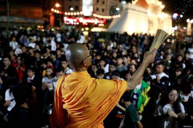 Description: A buddhist monk sprinkles holy water on Sunday as people pray for victims of the mass shooting in Nakhon Ratchasima, Thailand. From voanews.com