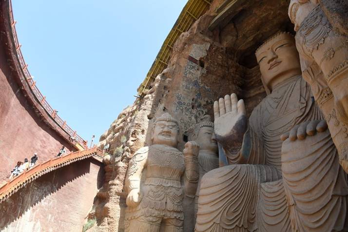 Tourists visit a stone Buddha in Tianti Mountain Grottoes in Wuwei City, northwest China's Gansu Province, on Aug. 20, 2021. Photo by Xinhua/Chen Bin.